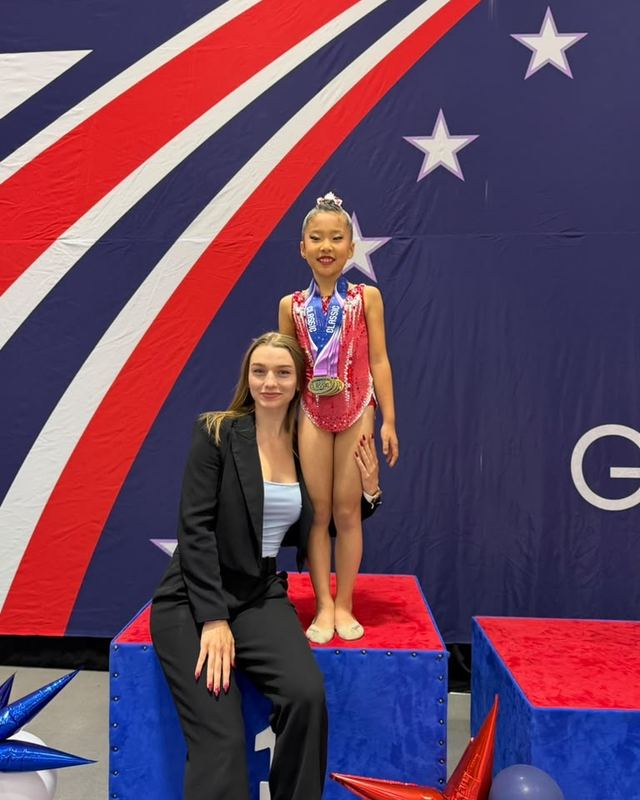 A gymnast and her coach on the podium after a state meet