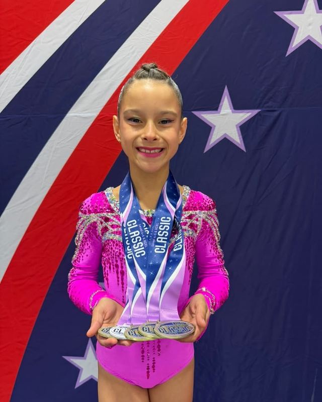 A gymnast holding a row of medals won across a single meet
