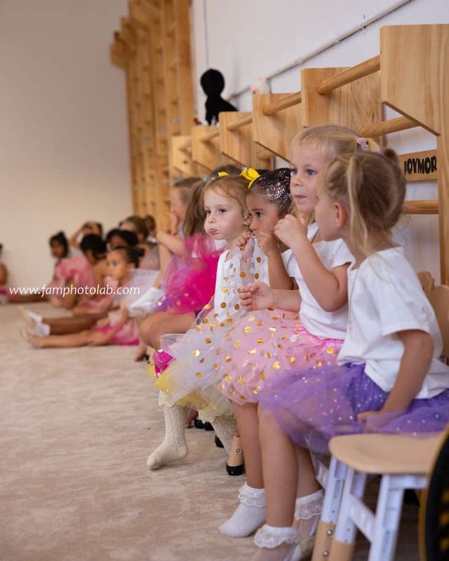 Gymnasts in sequinned tutus waiting on the bench for their turn