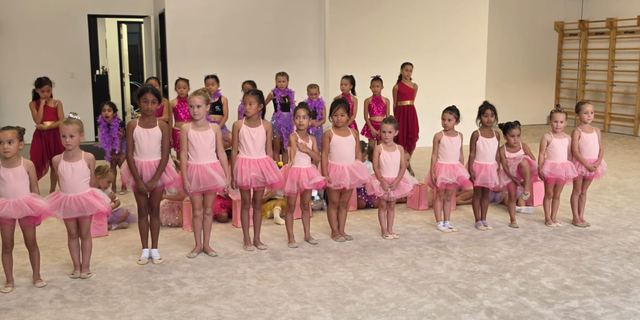 A long line of the youngest gymnasts in pink tutus waiting to perform